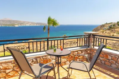 a balcony with a table and chairs and the ocean at Villa Forteza in Kalami