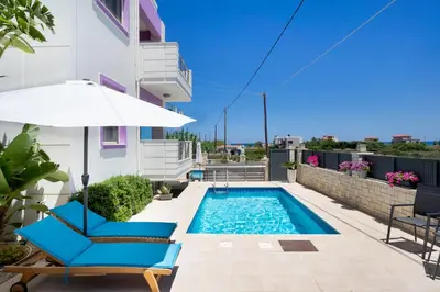 a patio with a swimming pool and two chairs and an umbrella at Geas House Ammos in Kolymvari