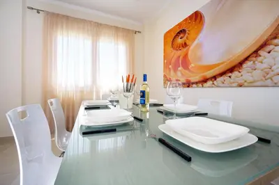 a dining room with a glass table and white chairs at Geas House Ammos in Kolymvari