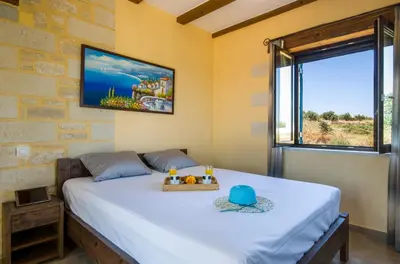 a bedroom with a bed and a tv on the wall at Villa Aliki - Traditional stone house with maximum privacy and stunning views ! in Xamoudhokhórion