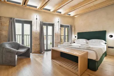 a bedroom with a large bed and a chair at Poem Suites in Chania Town