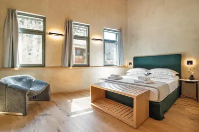a bedroom with a bed and a chair and windows at Poem Suites in Chania Town