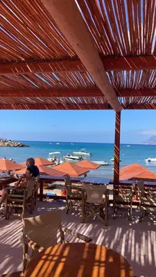 a person sitting on a deck with a view of the ocean at On the Beach in Kissamos