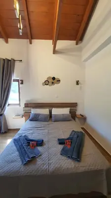 a bedroom with a large bed with blue pillows on it at Villa Anasa Residence in Varípetron