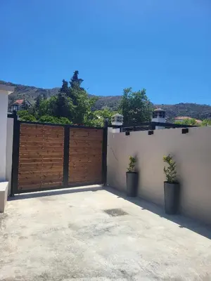 a garage with a wooden gate and two potted plants at Villa Anasa Residence in Varípetron