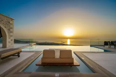 two chairs sitting on a swimming pool with the sunset at NAFSIKA XENIA-VILLA ARGO in Plátanos