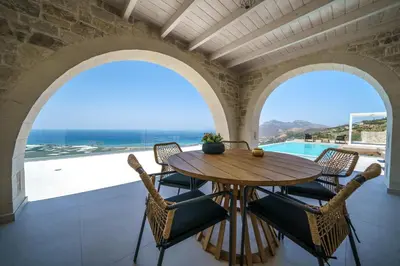 a dining room with a table and chairs and a view of the ocean at NAFSIKA XENIA-VILLA ARGO in Plátanos