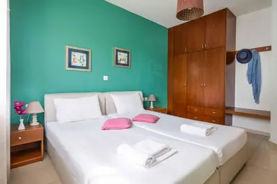 a bedroom with a large white bed with pink pillows at Villa Portokalia Platanias in Plataniás