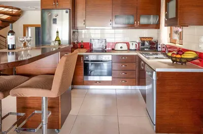 a kitchen with wooden cabinets and a counter top at Villa Portokalia Platanias in Plataniás
