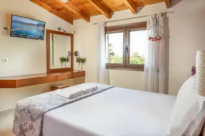a bedroom with a white bed and a window at Villa Portokalia Platanias in Plataniás