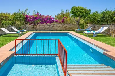 a swimming pool with a red rail in a yard at Villa Portokalia Platanias in Plataniás