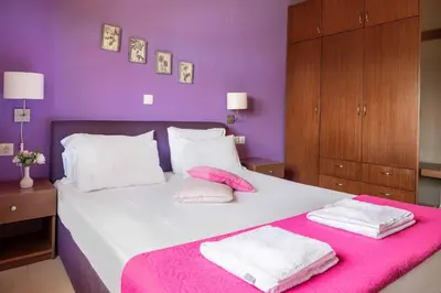 a purple bedroom with a bed with two towels on it at Villa Lemonia Platanias in Plataniás