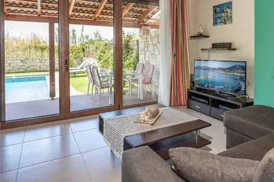 a living room with a television and a pool at Villa Mandarin Platanias in Plataniás