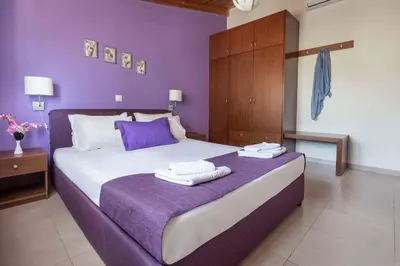 a purple bedroom with a bed with towels on it at Villa Mandarin Platanias in Plataniás