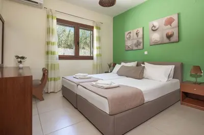 a bedroom with a large bed with green walls at Villa Mandarin Platanias in Plataniás