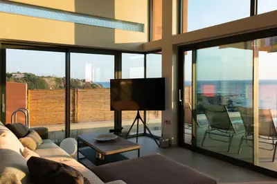 a living room with a couch and a flat screen tv at Casa Tarrha- Beachfront Villa with Heated Pool in Livadia