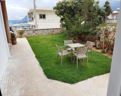 a table and chairs on the grass in a yard at Lenio's Apartment in Souda