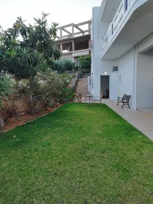a courtyard of a building with a green lawn at Lenio's Apartment in Souda