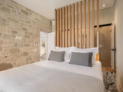 a bedroom with a large bed and a stone wall at Pietra Di Sabbia Villas in Palaiochóra