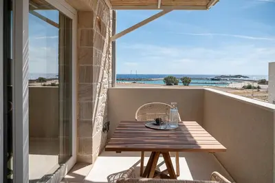 a table on a balcony with a view of the ocean at Pietra Di Sabbia Villas in Palaiochóra