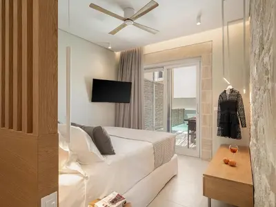 a bedroom with a bed with a ceiling fan at Pietra Di Sabbia Villas in Palaiochóra