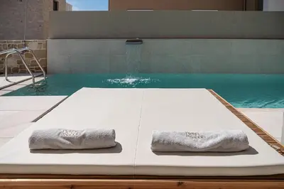 two towels sitting on a table next to a swimming pool at Pietra Di Sabbia Villas in Palaiochóra