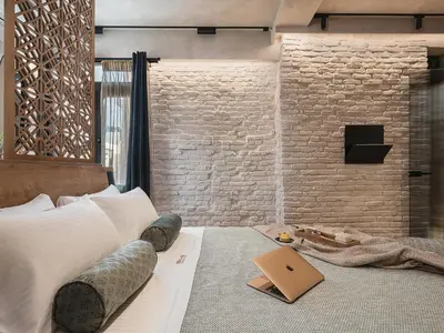 a bedroom with a brick wall and a laptop on a bed at Mimosa Minaret Jacuzzi Old Town Chania in Chania Town