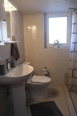 a bathroom with a sink and a toilet and a window at Bayside Apt. in Souda