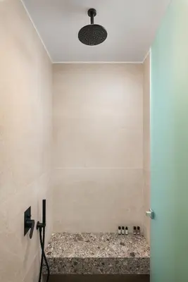 a bathroom with a shower with a stone floor at Raviewha Luxury Apartments in Ravdhoúkha
