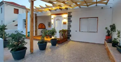 a patio with potted plants and a wooden pergola at The Nook in Maleme