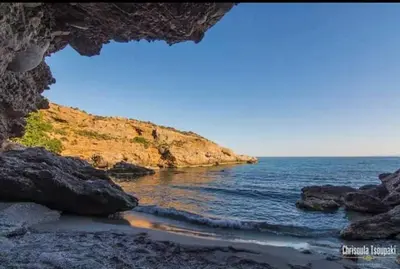 a view of the ocean through a rock cave at Votsalo House in Khóra Sfakíon