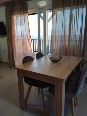 a wooden table and chairs with a view of the ocean at Votsalo House in Khóra Sfakíon