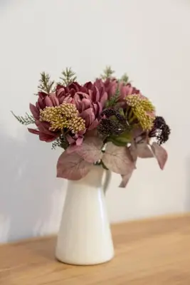 a white vase with a bouquet of flowers at Kyril Apartment in Chania Town