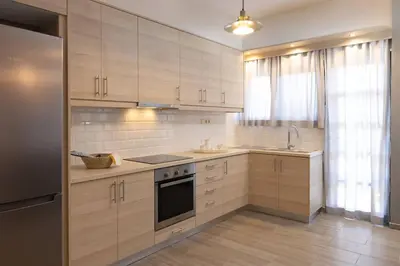 a kitchen with white cabinets and a sink and a refrigerator at Kyril Apartment in Chania Town