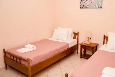 a bedroom with two beds and a table with a lamp at Olivia House -BY APOKORNAS VILLAS in Káïna