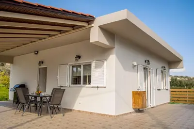 a white house with a table and chairs at Olivia House -BY APOKORNAS VILLAS in Káïna