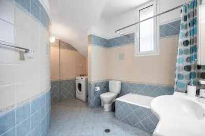 a blue tiled bathroom with a toilet and a sink at Sofie's Garden View Apartment in Daratso