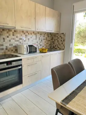 a kitchen with wooden cabinets and a microwave and a table at NICOL's HOUSE in Chania Town