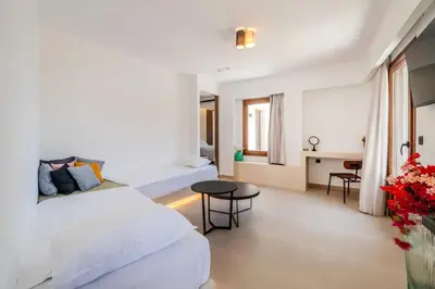 a bedroom with two beds and a table and a desk at VENTUS Luxury Suites in Khóra Sfakíon