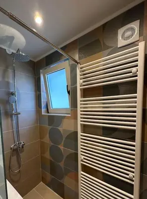 a bathroom with a shower and a window at Sunny flat among olive trees, next to the beach in Módhion