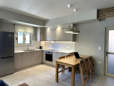 a kitchen with a table with a laptop on it at Sunny flat among olive trees, next to the beach in Módhion