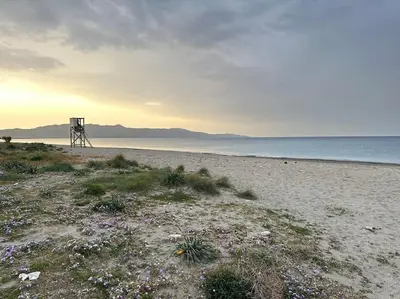 a chair sitting on a beach next to the ocean at Sunny flat among olive trees, next to the beach in Módhion