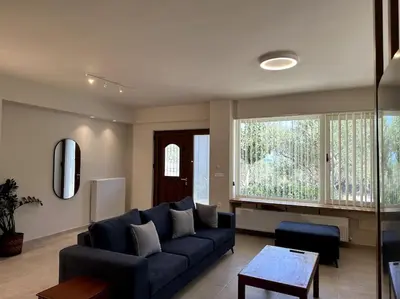 a living room with a blue couch and a large window at Sunny flat among olive trees, next to the beach in Módhion