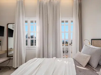 a bedroom with white curtains and a bed and a window at Casa Benedetta in Chania Town
