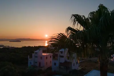 a sunset view of a building and a palm tree at Bella Vista Casa in Chania Town