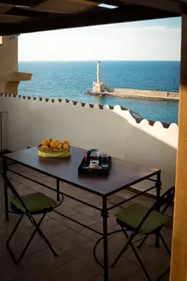 a table with a bowl of fruit and a lighthouse at In Heart of Old Town w. Venetian Port Views in Chania Town