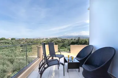 a balcony with chairs and a table with a view at Olive Grove Apartment in Chania Town