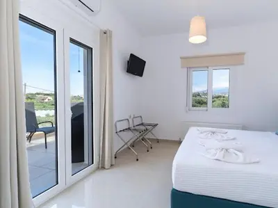 a white bedroom with a bed and a balcony at Olive Grove Apartment in Chania Town
