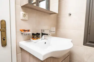 a bathroom with a white sink and a mirror at Be Crete - Solis maisonette in Chania Town