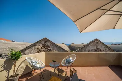 a patio with two chairs and a table and an umbrella at Be Crete - Solis maisonette in Chania Town